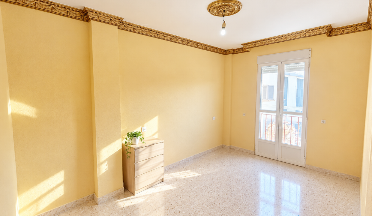 Dormitorio luminoso con molduras doradas y planta