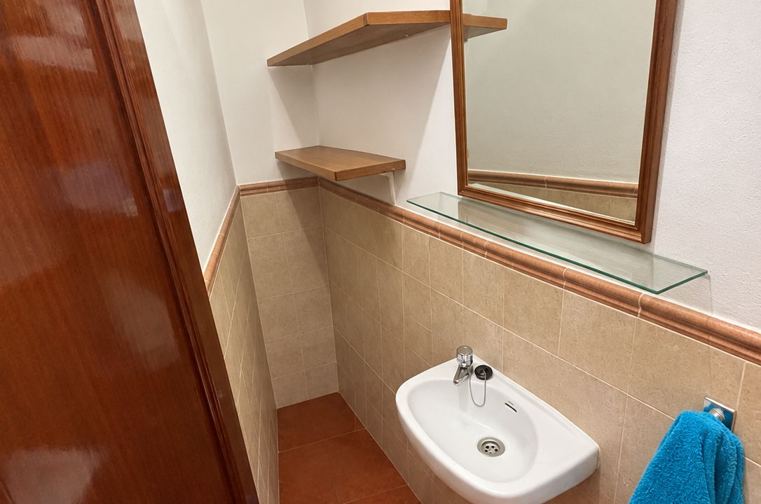 Lavabo estrecho con azulejos terracota y espejo
